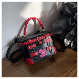 Detail of red and black box bag with pink cartoon rabbit and metal decorative buckles
