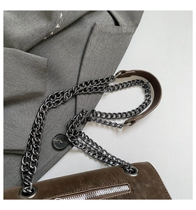 Macro detail of vintage leather texture and silver chain strap on a brown crossbody bag