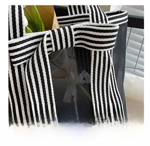 Detail of striped handles and black mesh fabric on a stylish tote bag for women