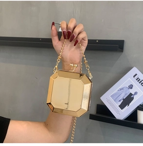 Detail of a golden mirror-finish acrylic box bag with beaded chain and octagonal design