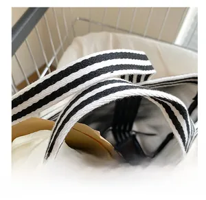 Close-up of durable black and white striped woven handle on canvas tote bag