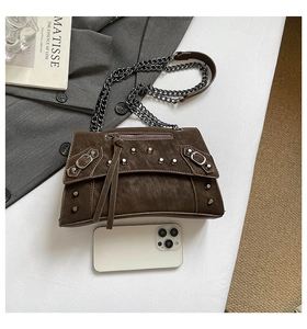 Brown rivet crossbody bag detail showing matte leather texture and metal chain with phone