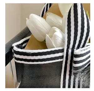 Close-up of tight stitching detail on black mesh tote bag with striped ribbon handles