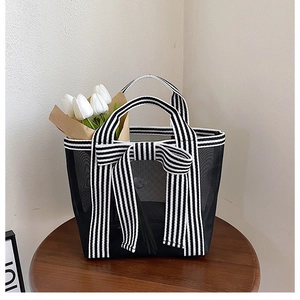 Detail of transparent mesh tote bag featuring black and white striped ribbon bow decoration