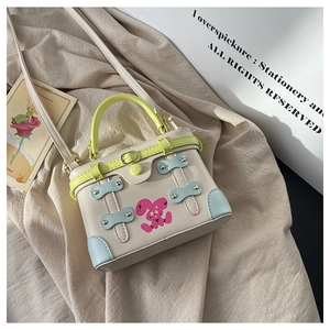 Detail of cream leather box bag featuring vibrant green handles and pink bunny print