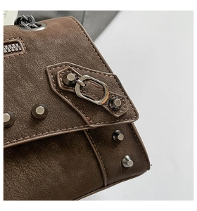 Detail view of brown vintage rivets and metal buckle hardware on a crossbody bag