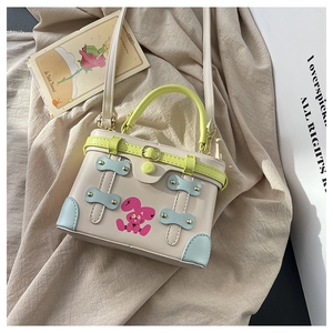 Close-up of a mini box bag with green handles and a pink cartoon bunny print