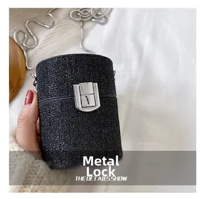 Close-up of mini cylindrical glitter bag featuring a silver metal lock and snake chain