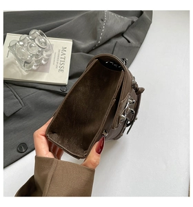 Macro shot of brown rivet chain bag with soft matte leather texture and interior space