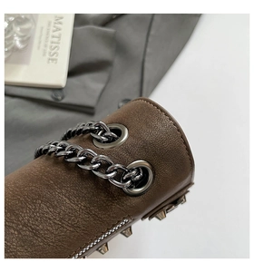 Detail of brown lychee leather crossbody bag with black rivets and thick chain strap
