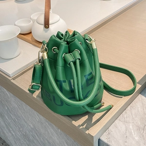 Chic green pebbled leather bucket bag with top handle and adjustable shoulder strap