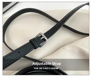 Macro view of adjustable black leather shoulder strap with polished silver buckle detail