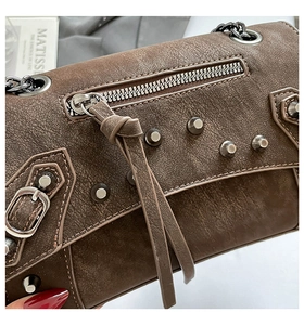 Detail of dark brown vintage rivet bag with fringe tassels and metallic chain strap