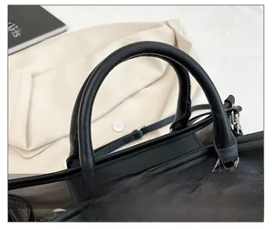Detail of floral embroidery on a black leather tote bag with sturdy handles