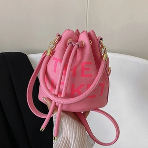 Detail of pink pebbled leather bucket bag featuring The Bucket printed text and gold hardware