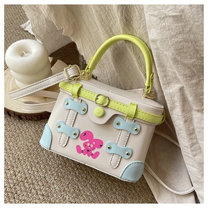 Detail of mini box bag with pink rabbit print, neon green handle and blue corners