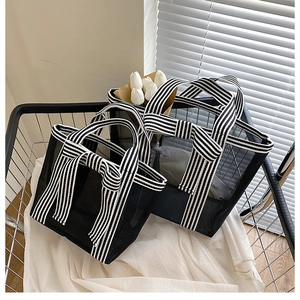 Detail of black mesh tote set with striped handles and bow in a clean lifestyle setting