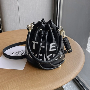 Detail of black pebbled leather bucket bag with THE BUCKET print and golden hardware