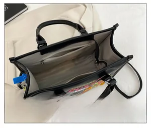 Interior view of large black tote bag featuring souvenirs print and spacious inner pocket