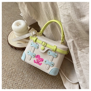 Detail of a box-style handbag featuring a pink bunny print and lime green handle