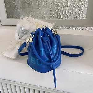 Detail of royal blue leather bucket bag with The Bucket text and gold hardware