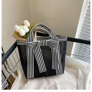 Detail of black mesh tote bag with large striped bow and stylish net fabric texture
