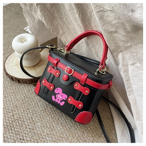 Close-up of black and red contrast box bag with cute rabbit print and gold metal hardware