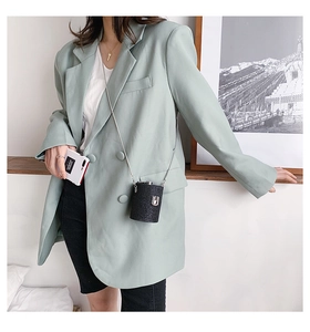 Mini black glitter cylindrical crossbody bag with silver chain worn with green blazer