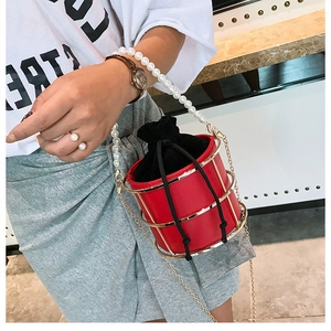 Dettaglio borsa a secchiello rossa con gabbia in metallo dorato e manico di perle