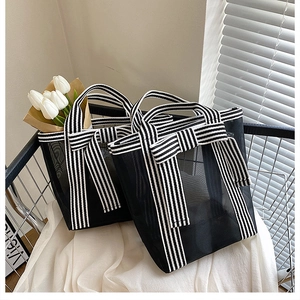 Detail of transparent black mesh tote bag with striped ribbon and large bow design