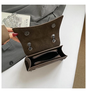 Detail of vintage brown matte leather bag featuring dual magnetic buckles and inner zip pocket