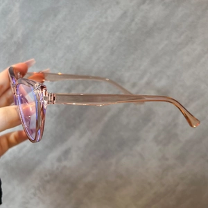 Close-up of translucent pink cat-eye frame with blue light blocking lenses in hand