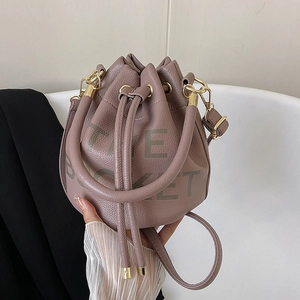 Close-up of pink lychee grain leather bucket bag with THE BUCKET text and gold hardware