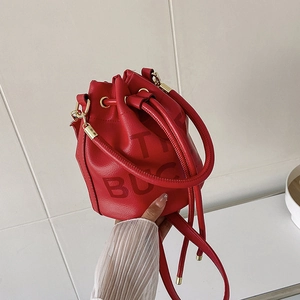 Detail of red bucket bag showing drawstring, golden hardware and embossed BUCKET text