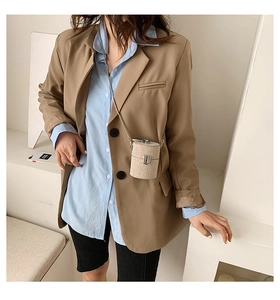 Close-up of mini cylindrical chain bag with woven texture worn over a khaki blazer