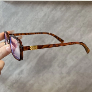 Close-up of tortoise shell glasses frame with gold metal hinges and anti-blue light lens