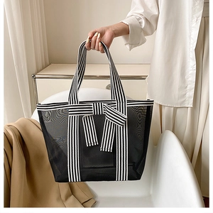Detail of black mesh tote bag featuring chic black and white striped bow and handles