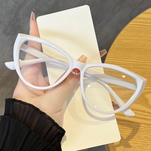 Close-up of white cat-eye fashion glasses frame held by hand showing lens details