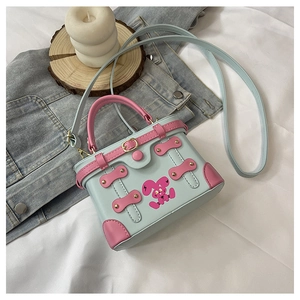 Detail of mint green box bag with pink handles and cartoon print on white bedding