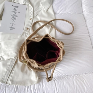 Detail of beige bucket bag showing red fabric interior lining and dual compartments