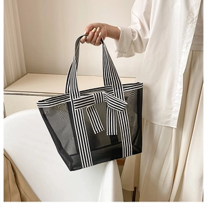 Close-up of black mesh tote bag featuring a striped bow and handle details