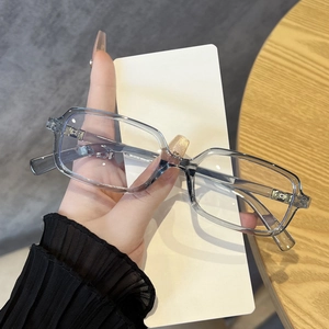 Detail of transparent gray square frame glasses with a metal cross ornament hinge