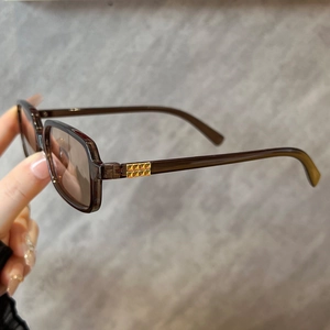 Detail of square brown sunglasses with golden rivet accents on the translucent frame