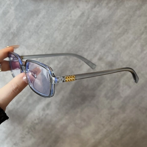 Detailed macro view of square translucent grey frames with golden stud accents and blue lenses