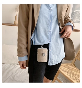 Close-up of woven cylinder mini bag with silver buckle worn as a stylish waist accessory