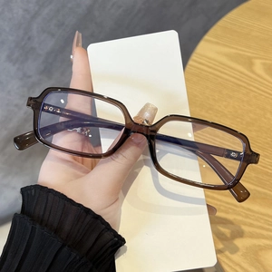 Detail showing transparent brown rectangular eyeglass frames held in hand for texture