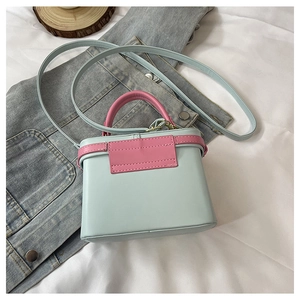 Detail view of mint green and pink box bag with gold-tone hardware on denim jacket