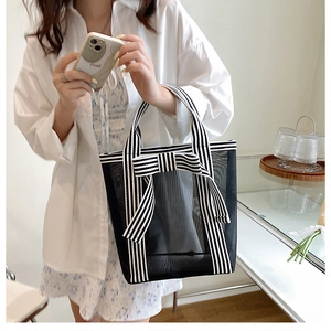 Detail of black mesh tote bag with striped ribbon bow and textured fabric finish