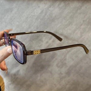 Detail of square brown transparent eyewear frame with golden rivets and blue light lens