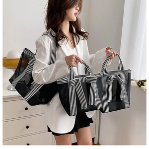 Detail of minimalist black mesh tote bag with striped ribbon handle shown on a model